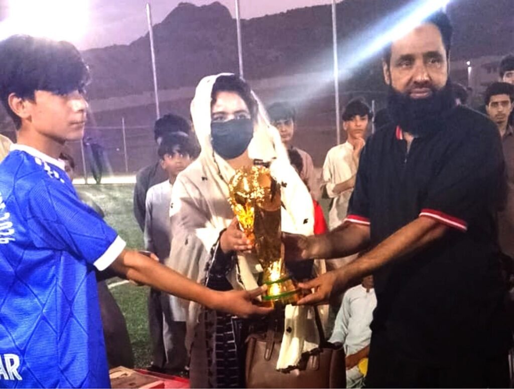 District Sports Officer Khuzdar Ruqaiya Obaid pehla All Khuzdar Futsal Tournament ke Mohsin Hasan Academy ke captain ko runner-up trophy de rahi hain